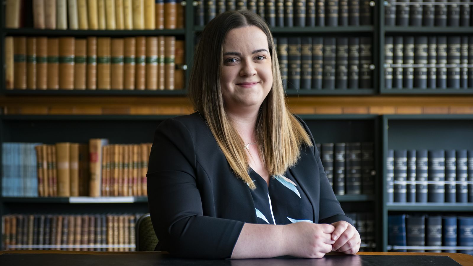 Joanna Bate sits in front of a book case in the Law School.