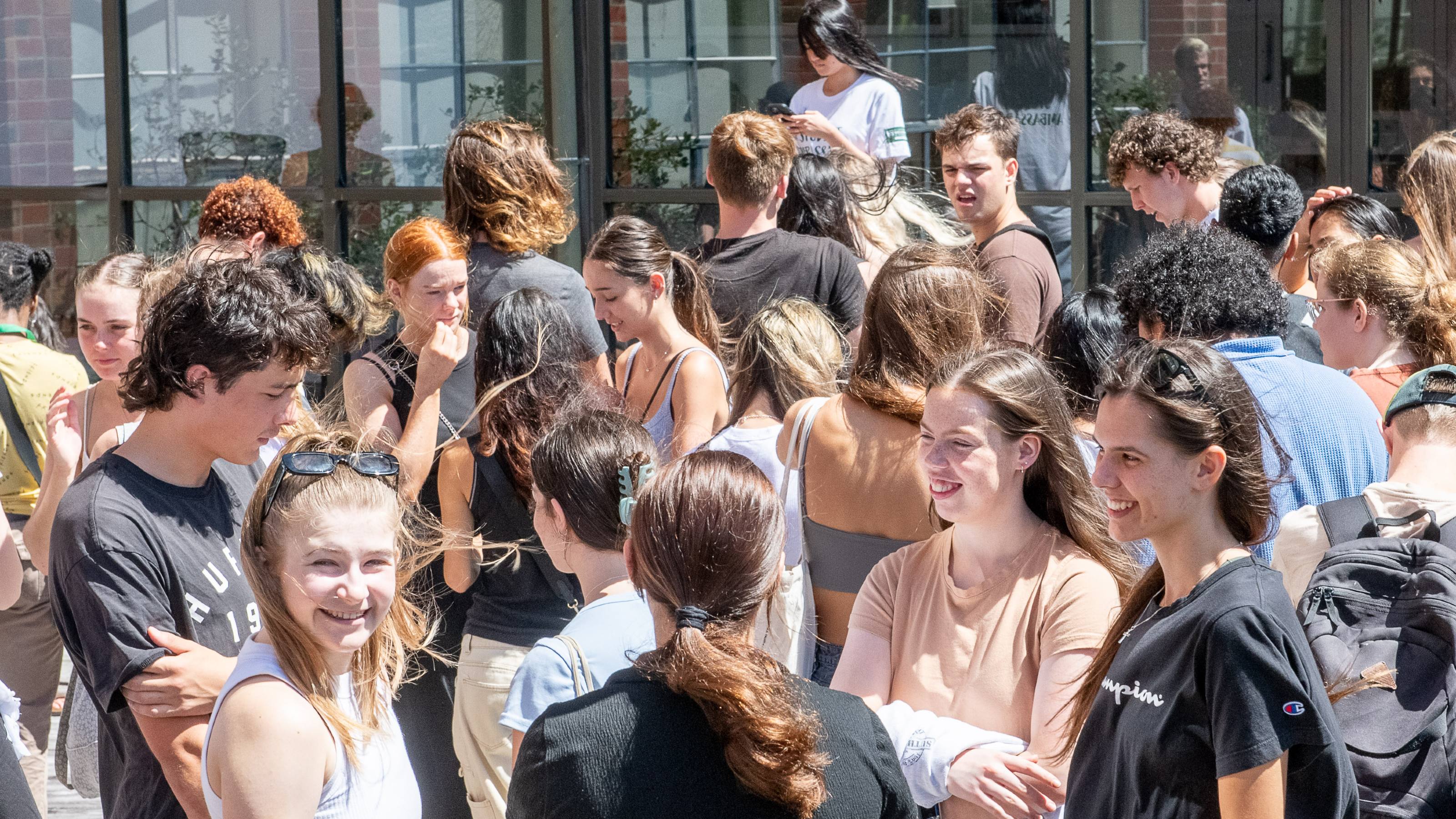 A crowd of students on campus outside on a sunny day.
