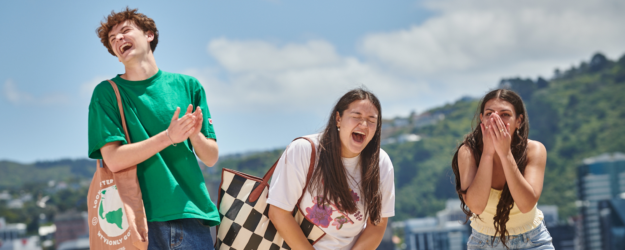 Three students walking along Oriental Beach, laughing.