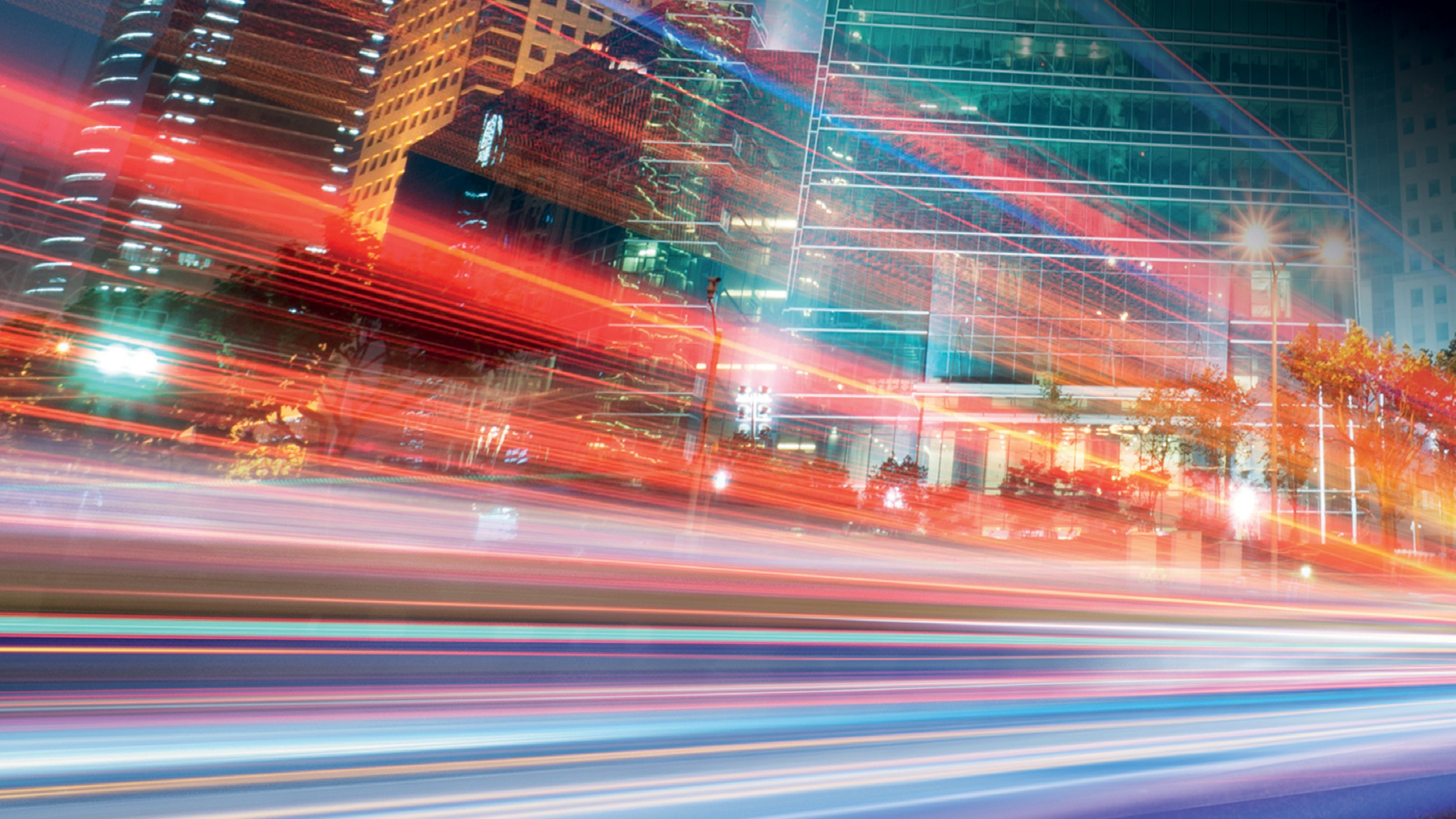 An image of a cityscape with many lines of light, as if timelapsed capturing the lights of cars as they drive past.