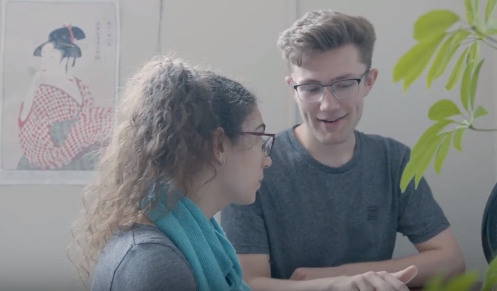 Jordan Schulde and Cameron Hartley discussing their studies in the Language Learning Centre with Japanese print in the background.
