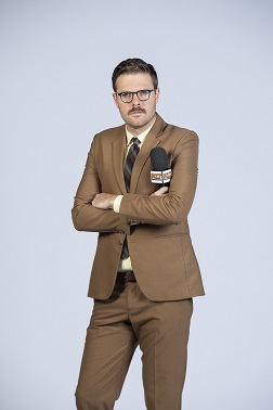 Comedian Guy Williams striking a pose with a microphone.