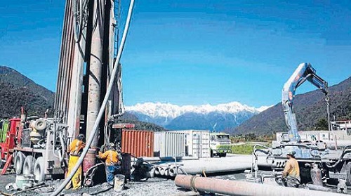 Machinery drilling and white capped mountains as background Deep fault drilling project