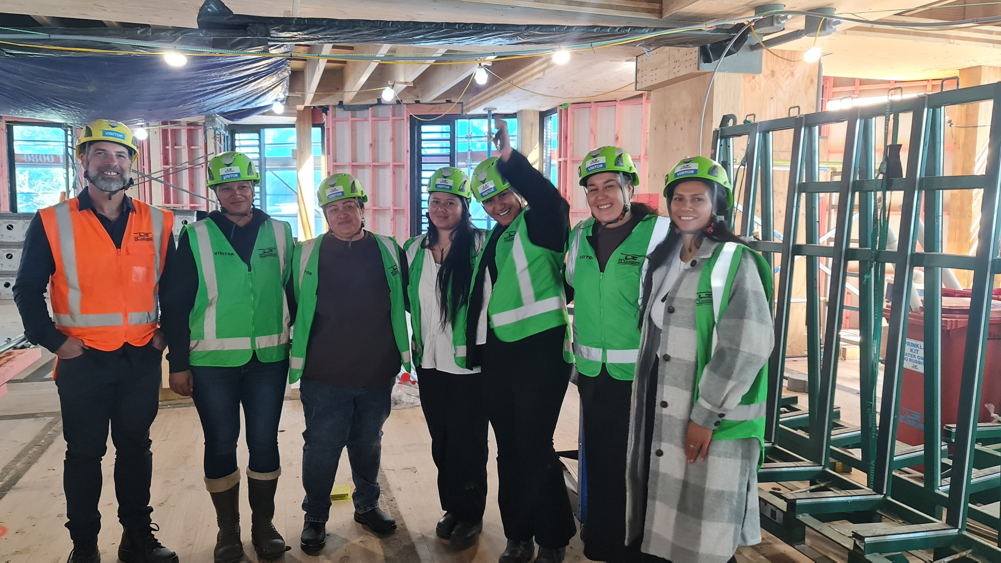 A group of people in hi vis vests and hard hats standing inside a construction site.