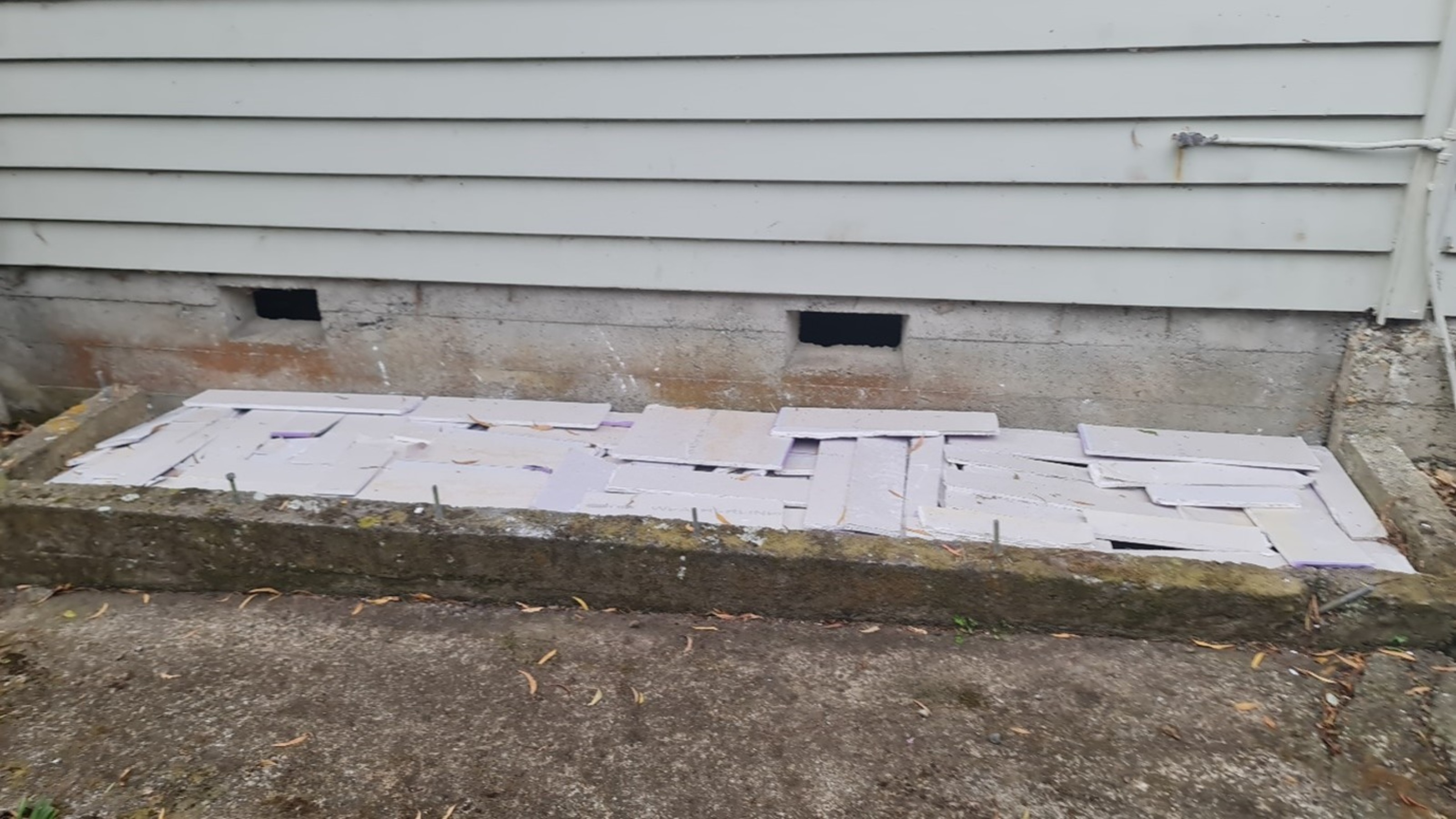 Offcuts of plasterboard laid out flat covering a garden bed. 