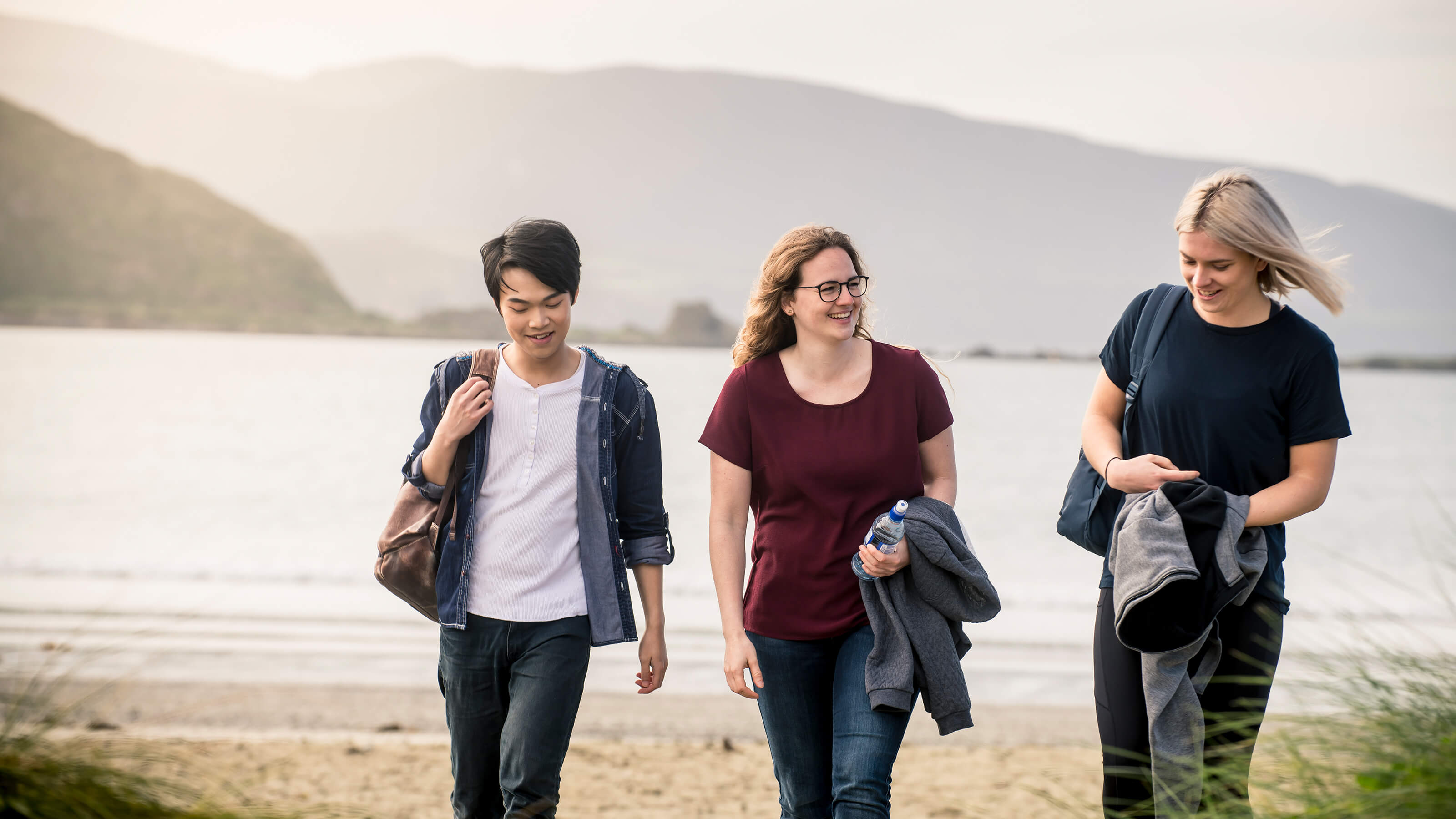 Three students walking across beach.