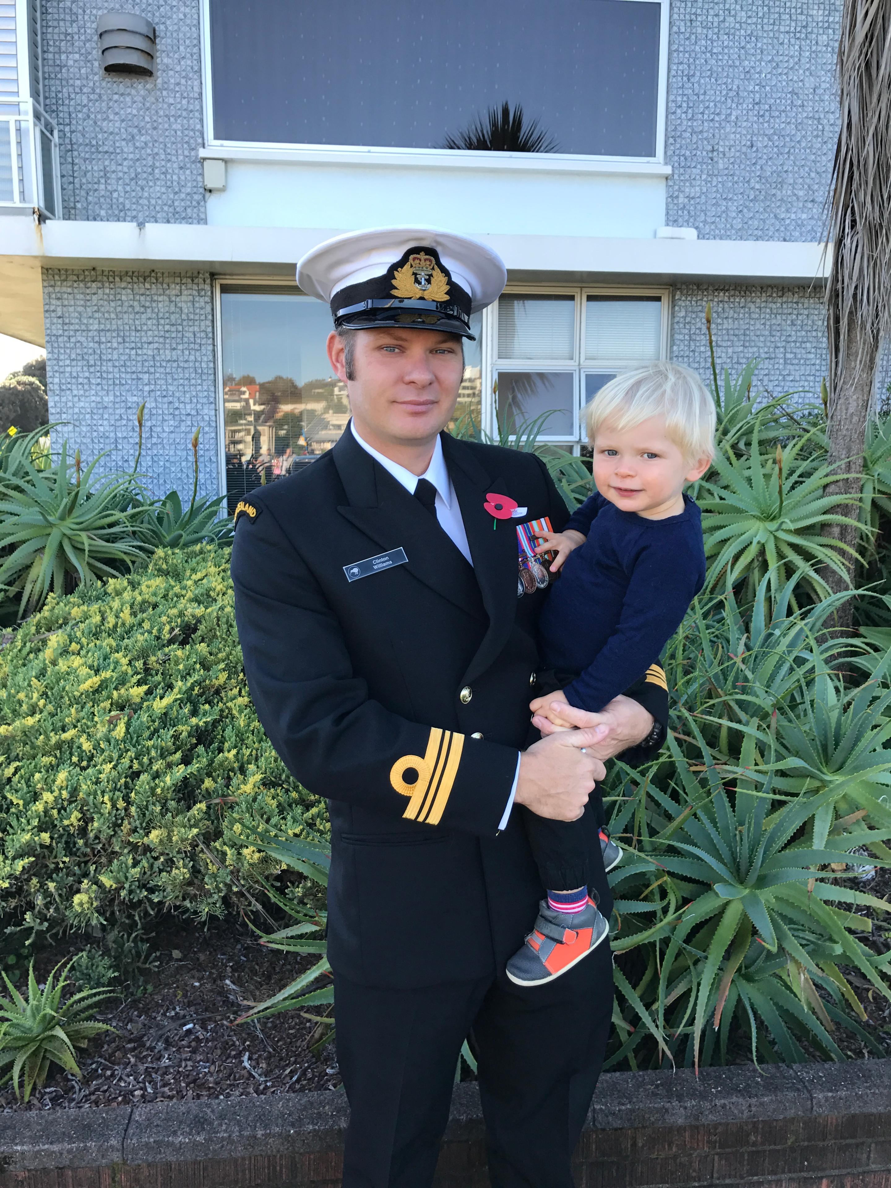 Clinton Williams in uniform on ANZAC day, carrying his child