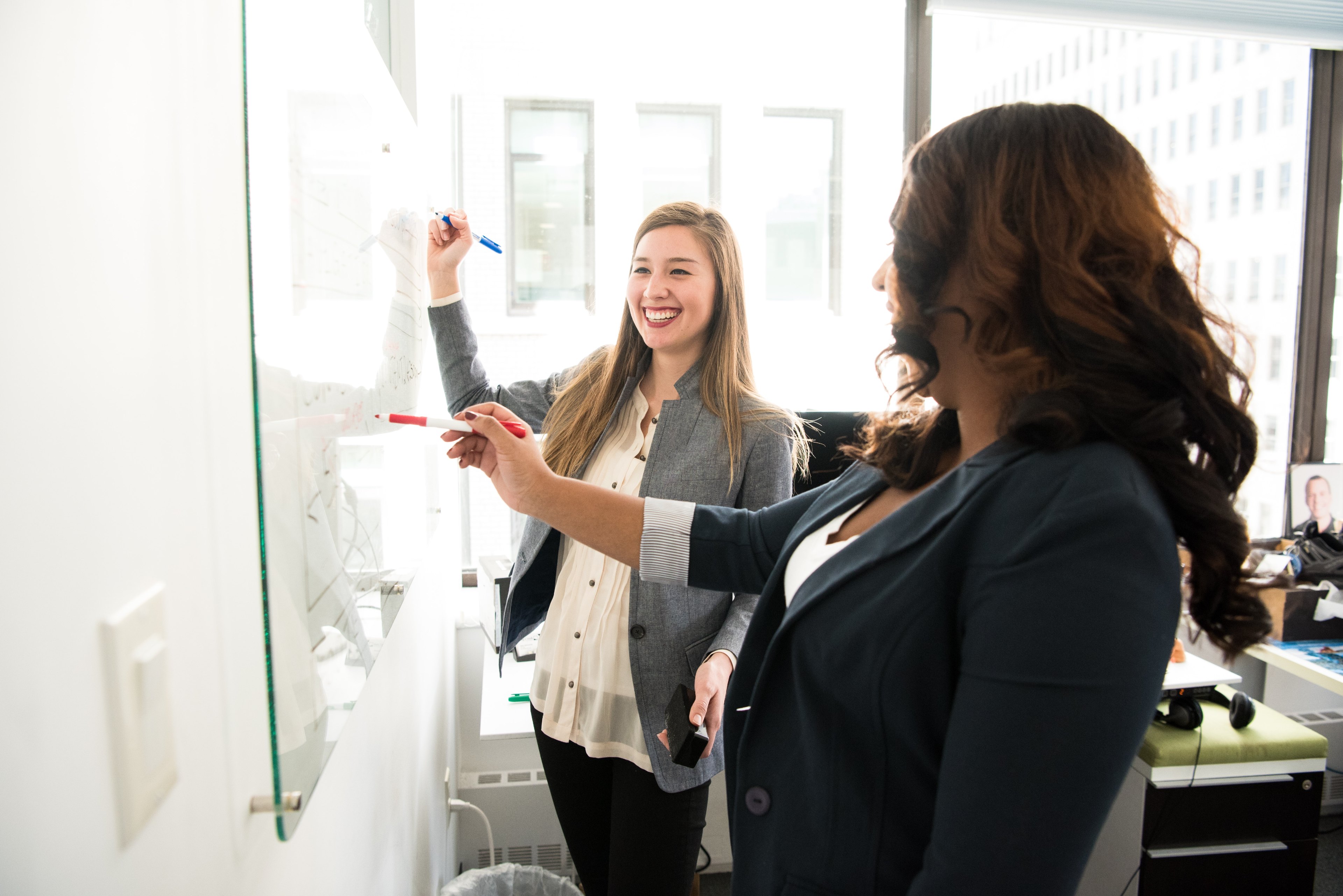 Image of two woman writing on a whiteboard