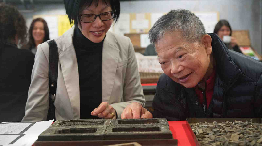 Winnie Chan and Laywood Chan look at decorative borders used for invitations. 
