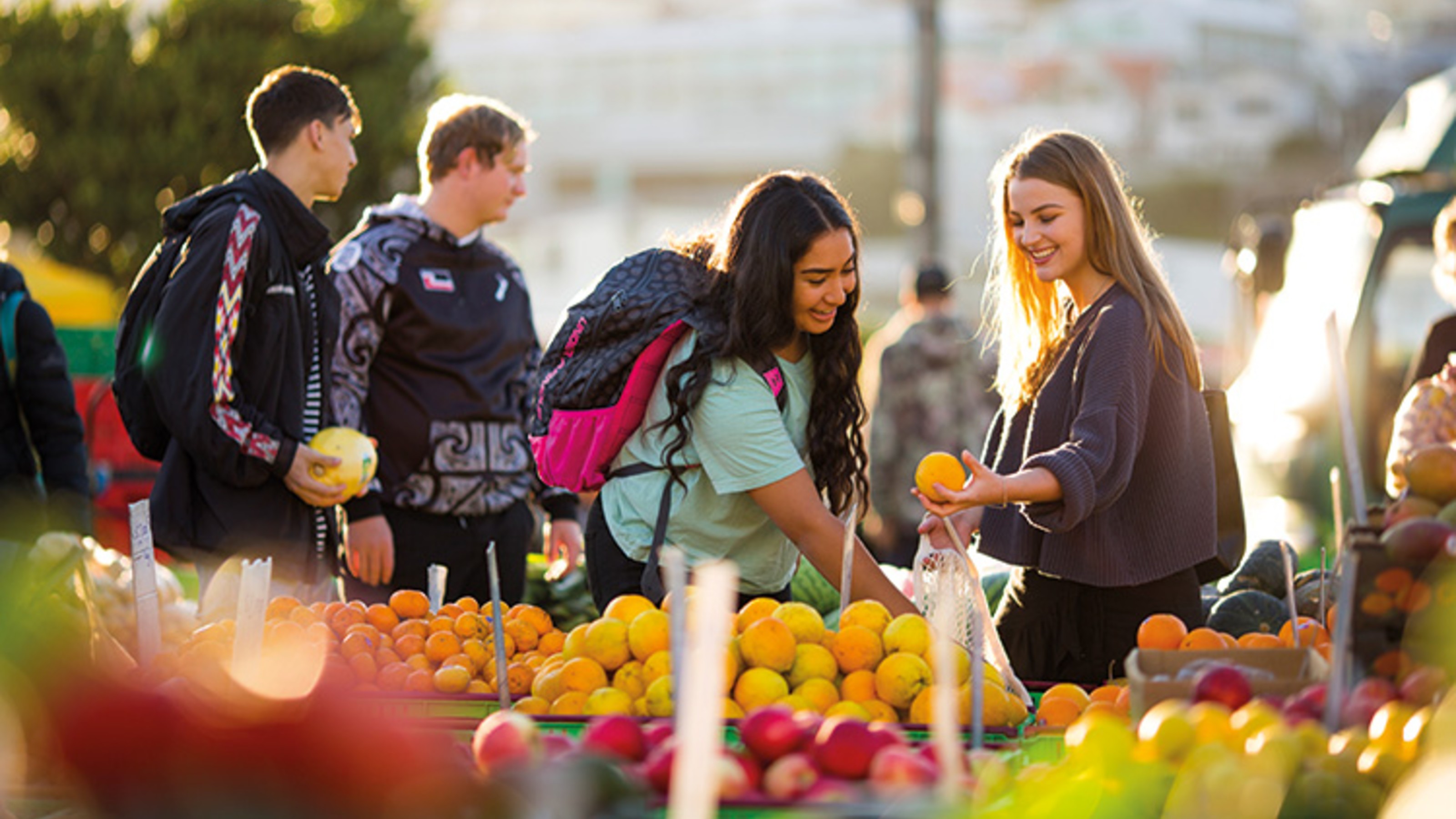 Two female students shop for fruit and vegetables at Wellington's Harbourside Market.