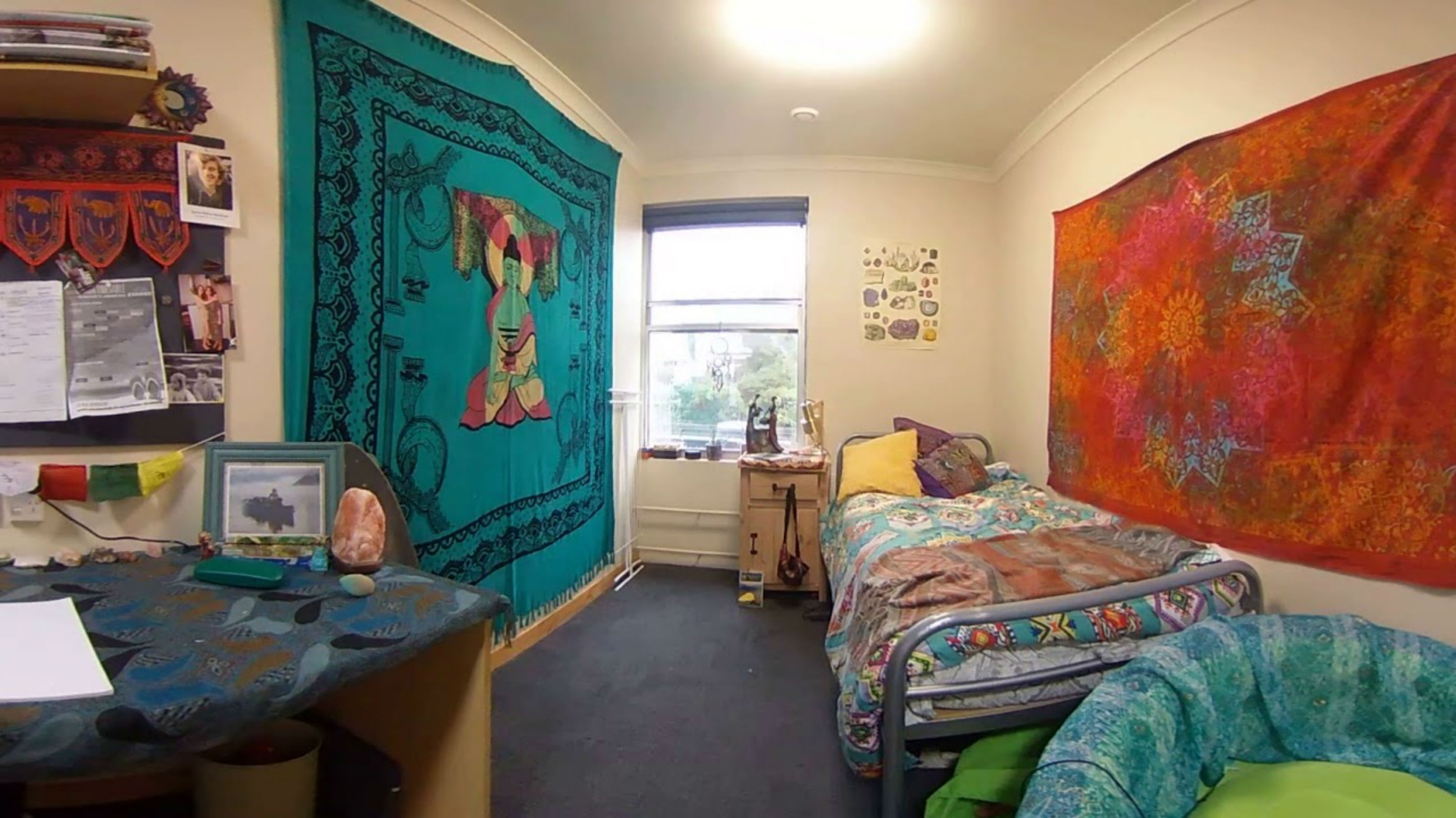 An occupied room with a single bed and a Buddhist theme.