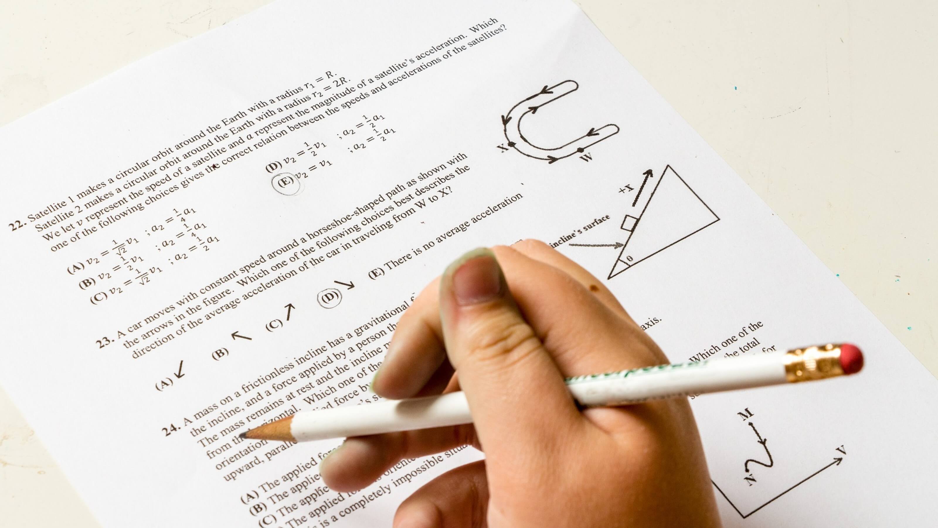 find-past-exams.jpg A close up of a hand holding a pencil filling in an exam paper.