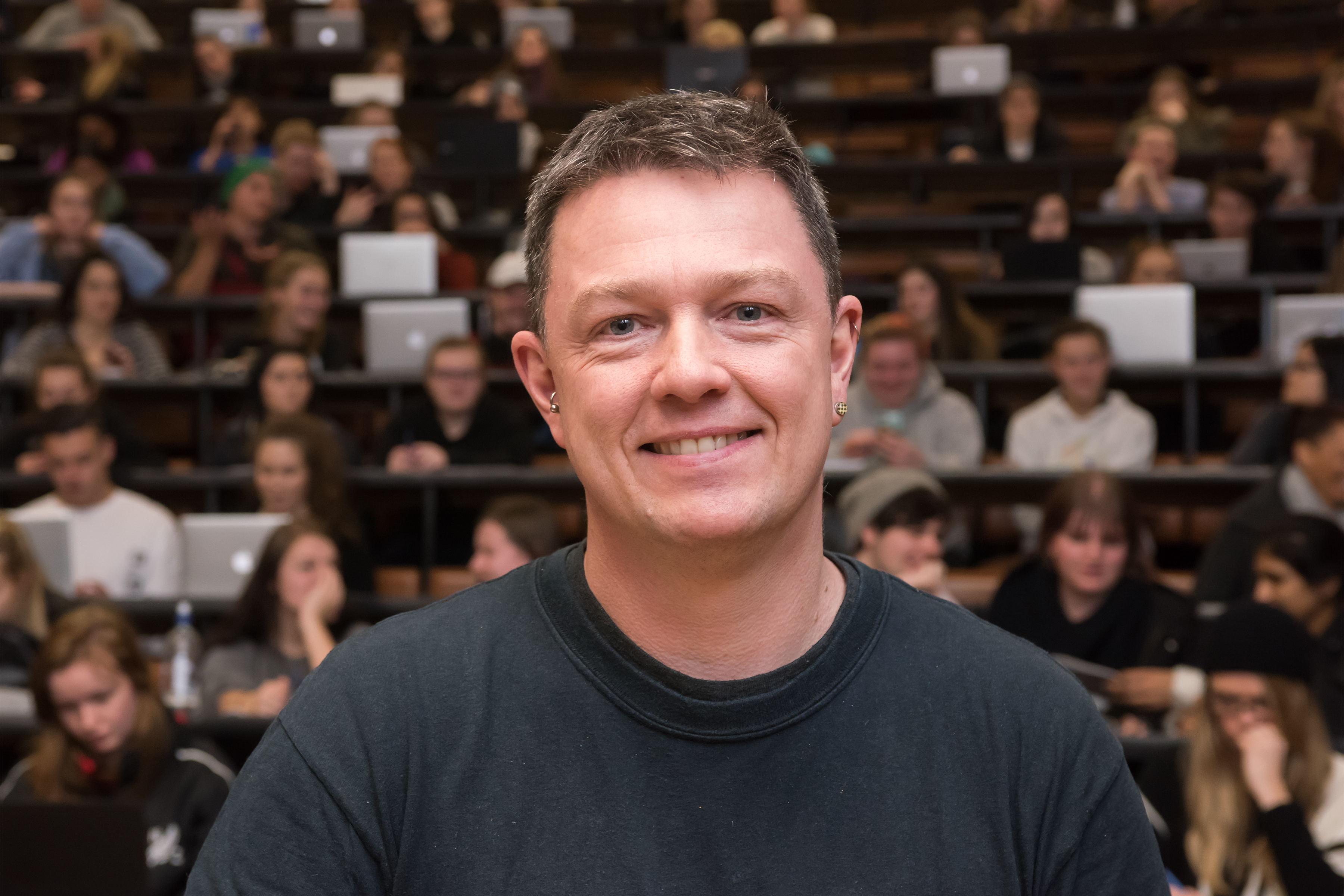 Professor Marc Wilson stand before a lecture theatre.