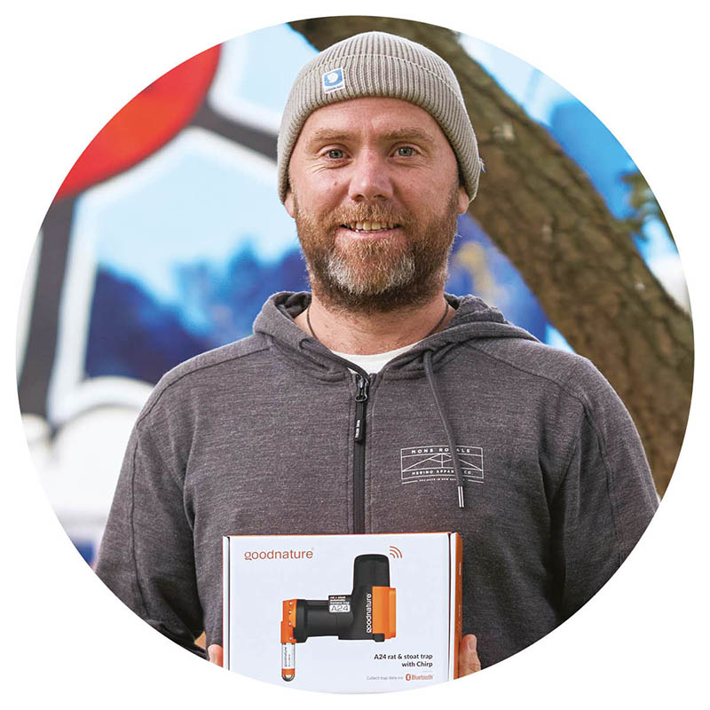 An upper body portrait of Robbie van Dam from Goodnature holding one of his company's traps.