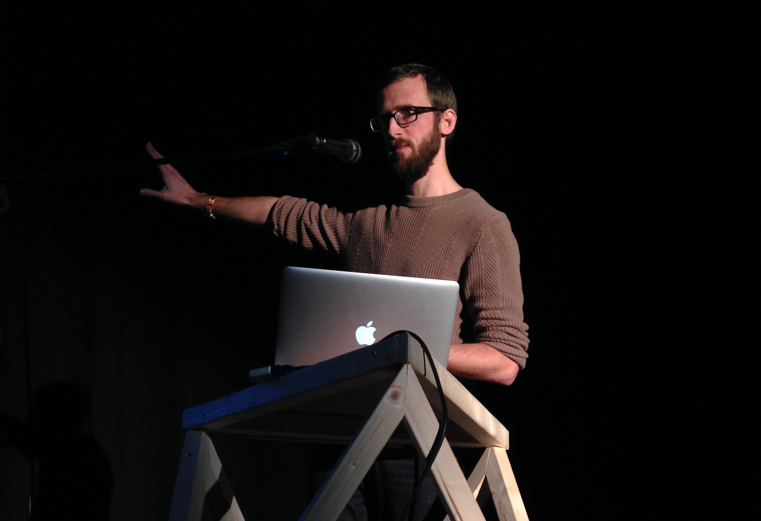 Pippin Barr presenting on stage at a conference.