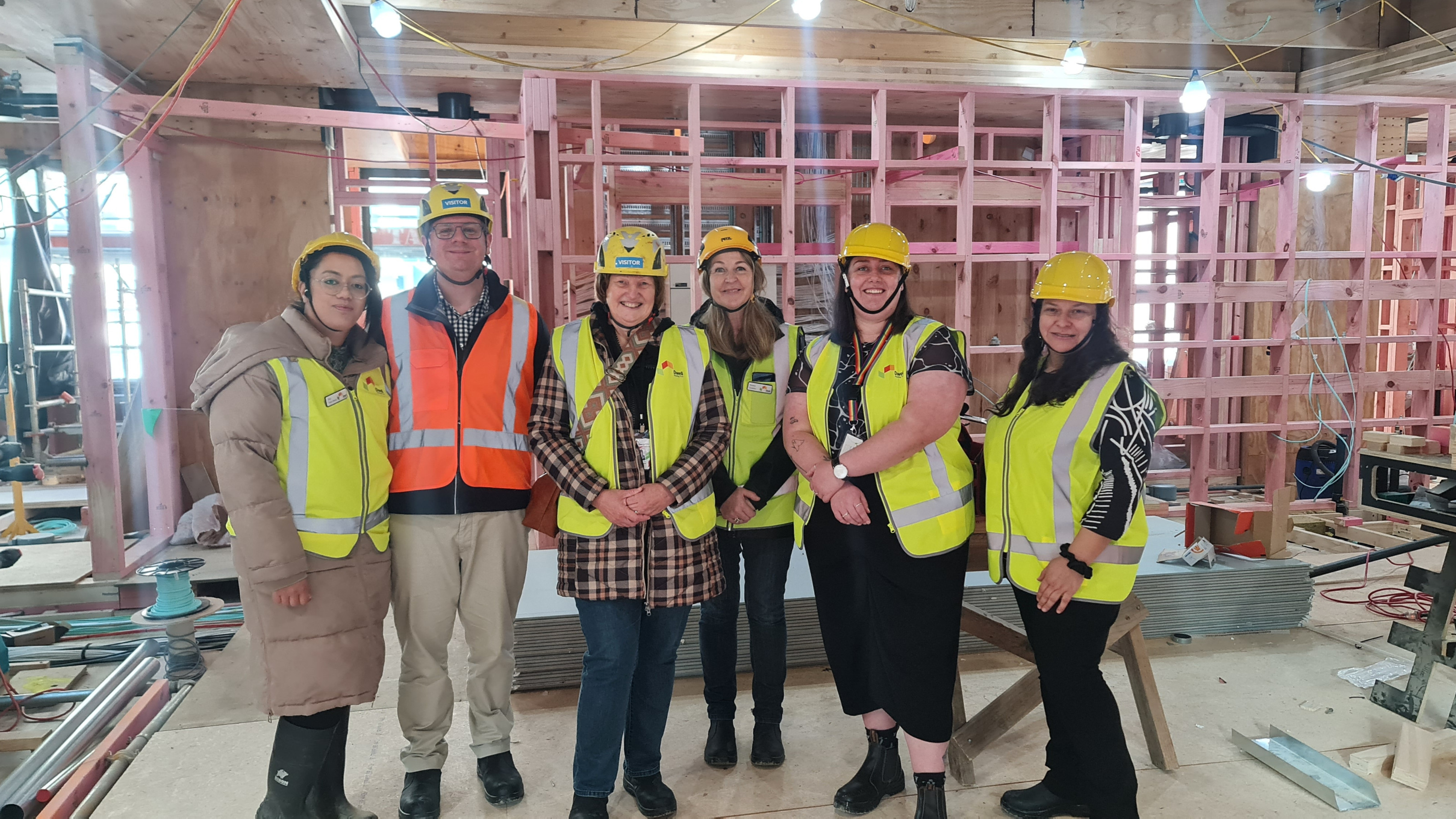 A group of people in hi vis vests and hard hats standing inside a construction site.