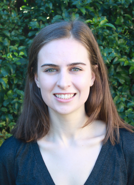 Student Victoria Munn stands smiling in front of trees.