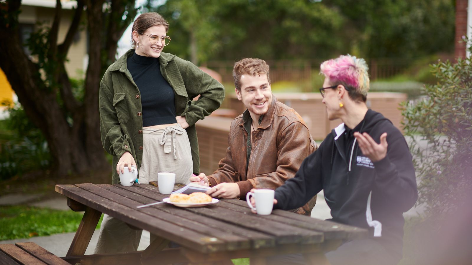 Residents sit outside on a picnic table, with an RA