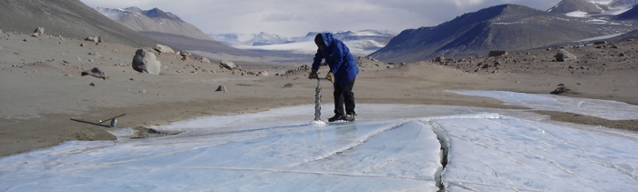 A researcher taking a permafrost core sample in Antarctica.