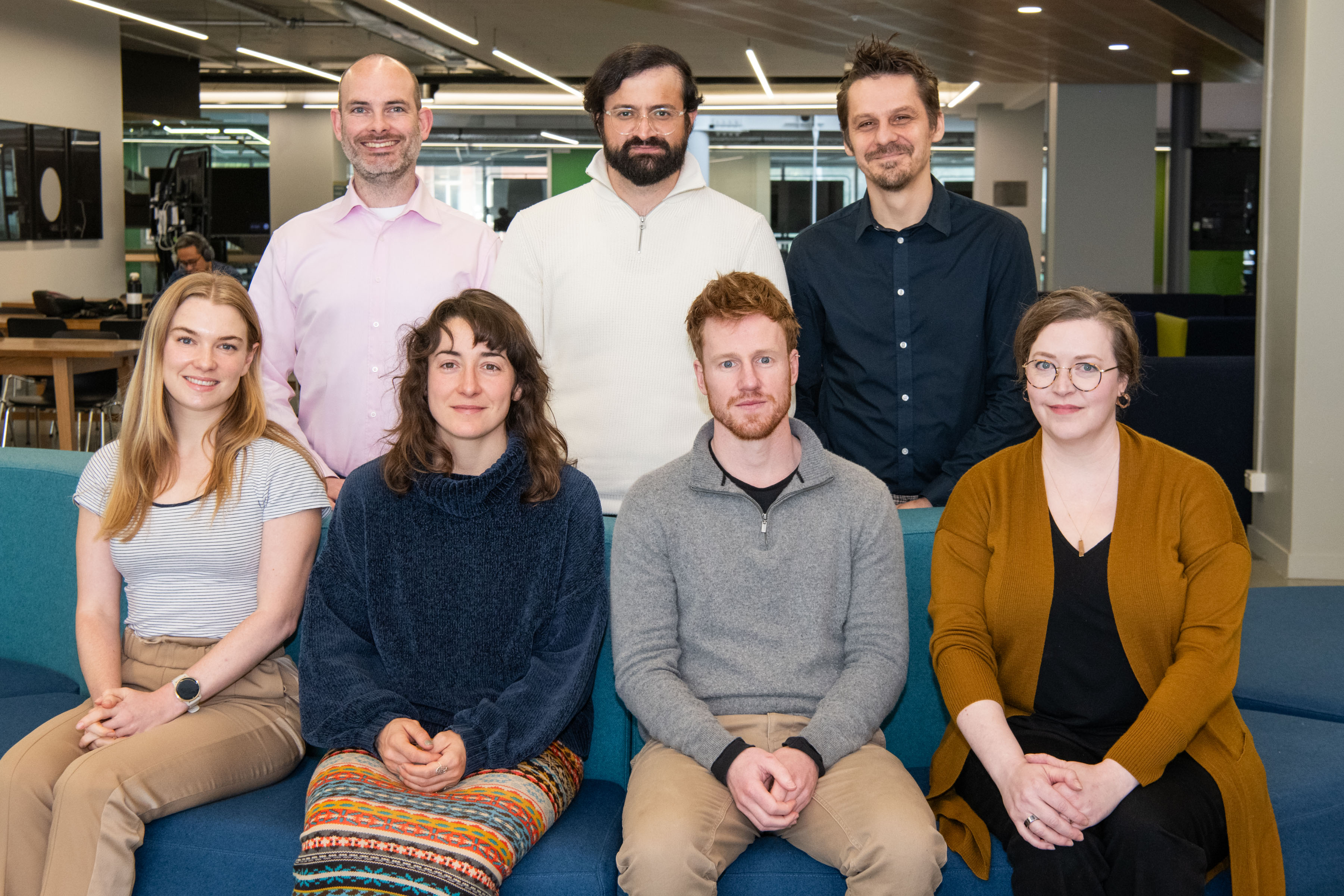 Seven people sit and stand in two rows for a group photo