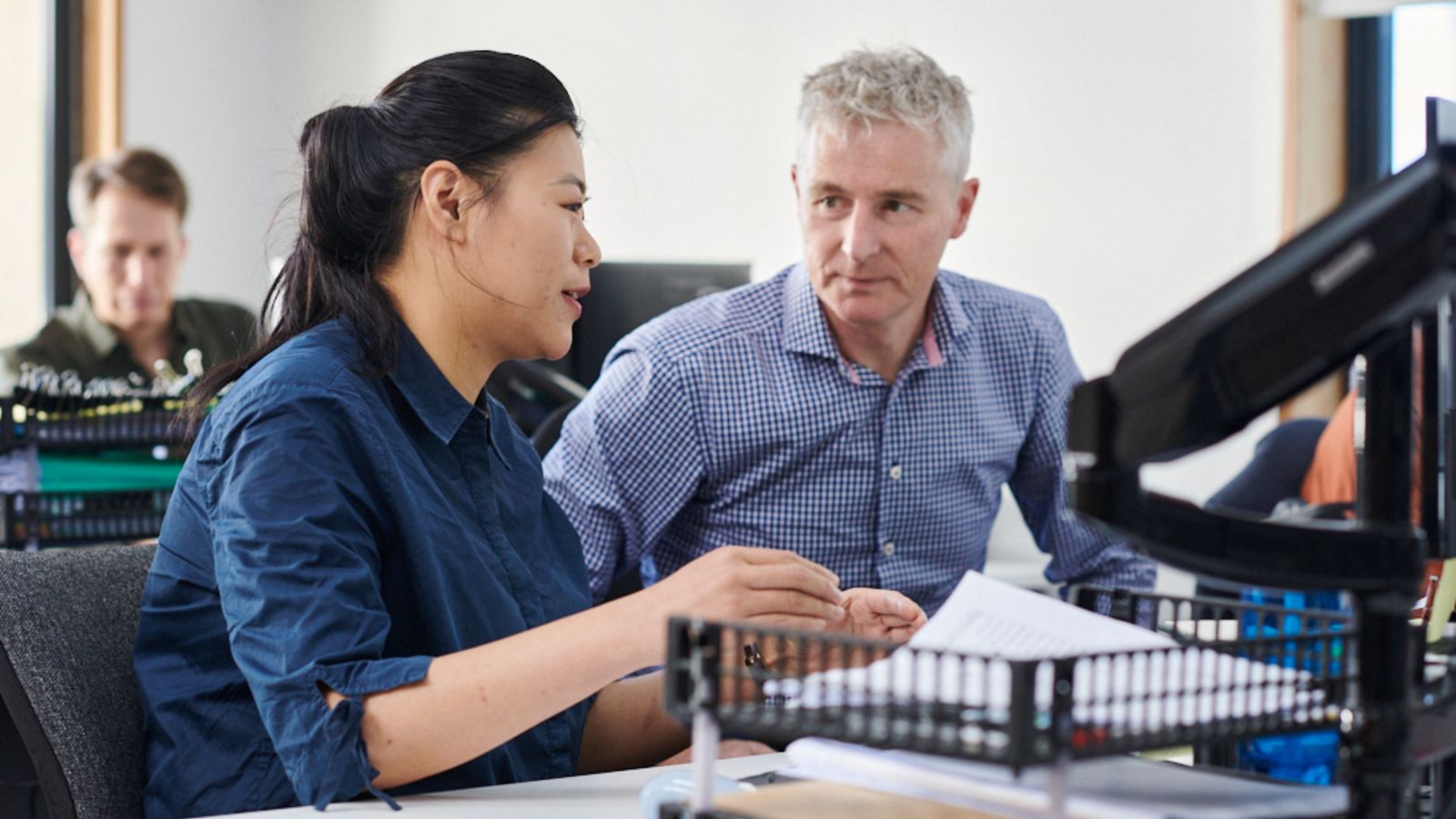 Business man talking to a student at a office desk.