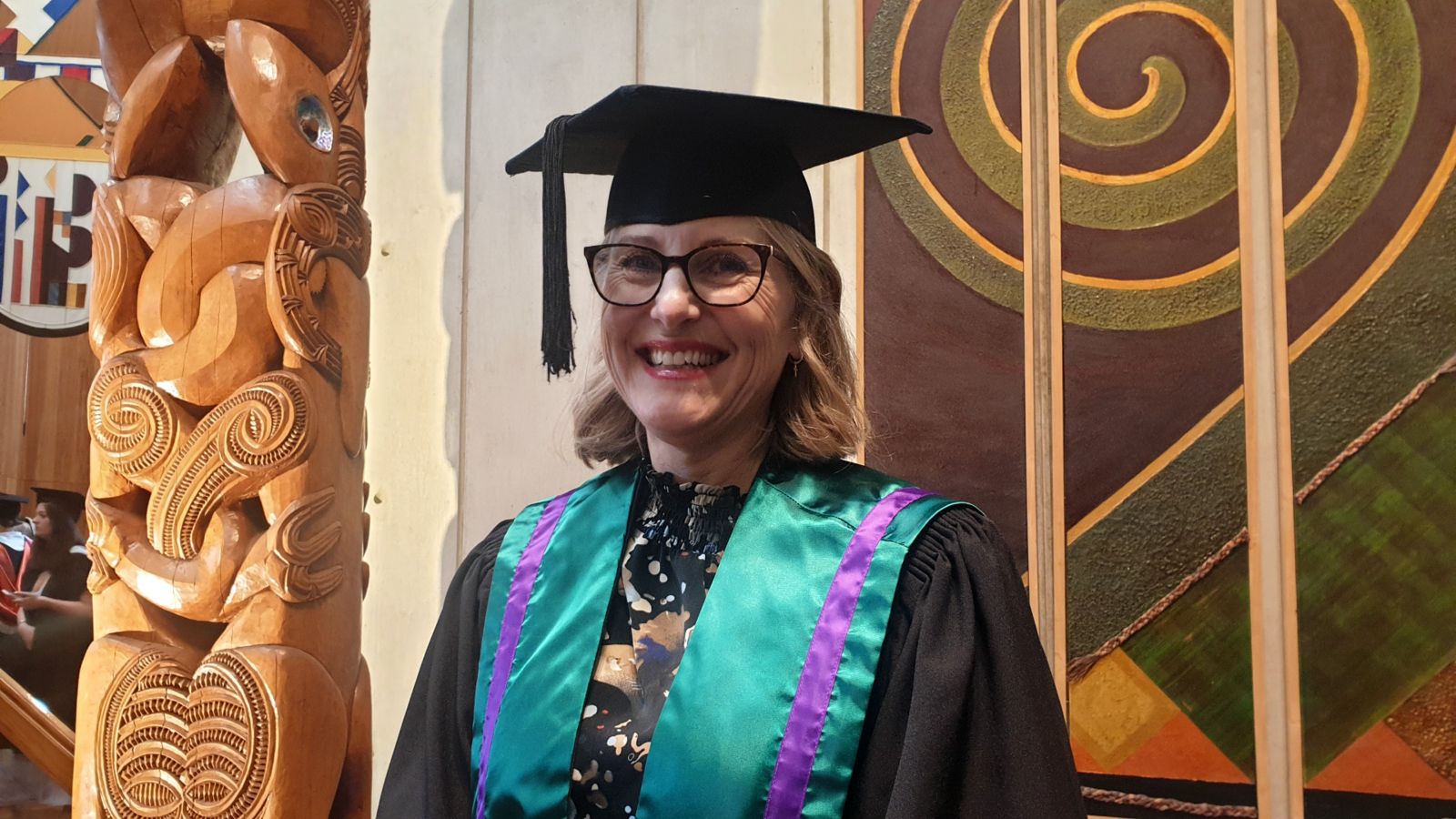 Robyn posing for a photo wearing her academic dress at graduation