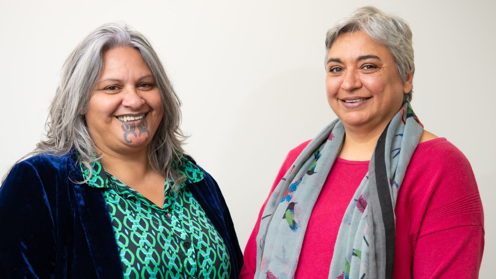 Two grey haired women smiling.