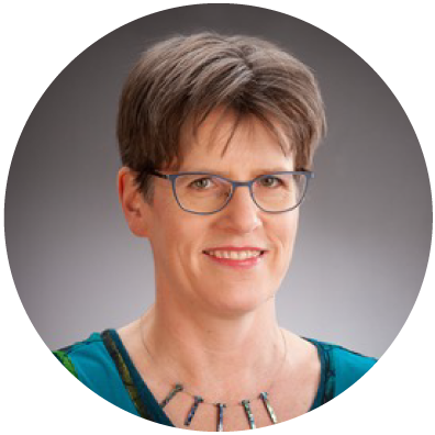 Woman with short brown hair and glasses smiling.