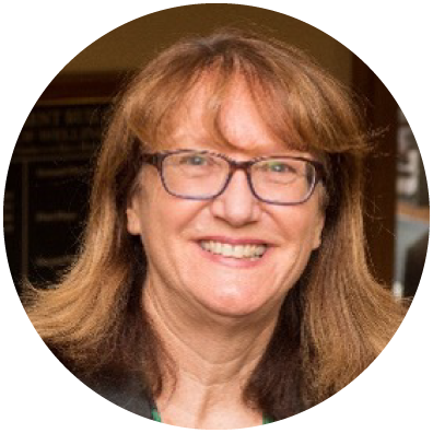 Woman with light brown hair and glasses smiling.