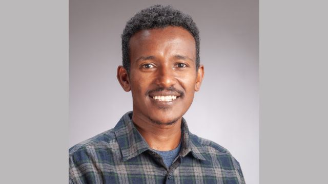 A portrait of Dessalegn smiling into the camera