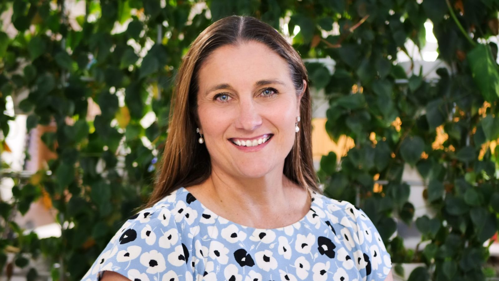 woman smiling with green leaves in background