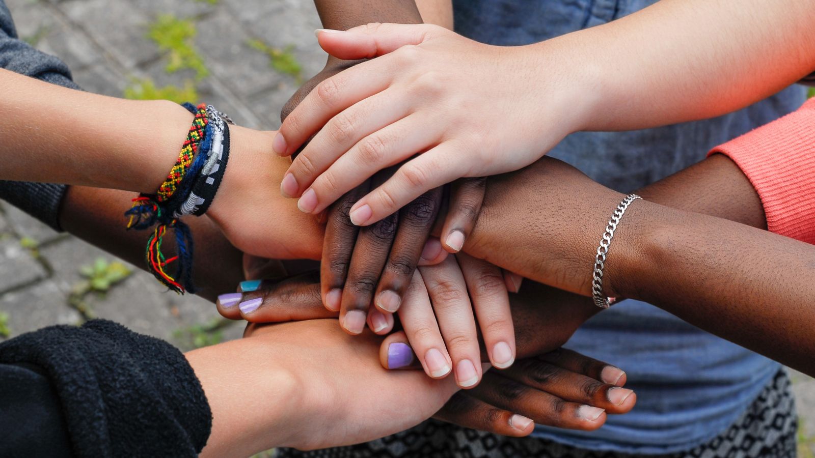 Four unseen women stack their eight hands in a huddle