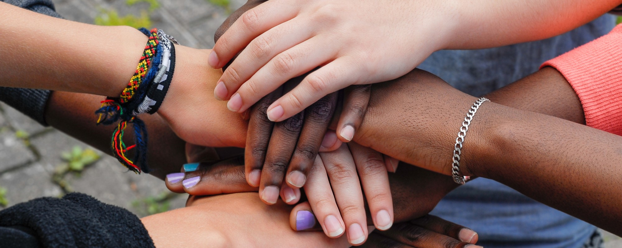 Four unseen women stack their hands in a huddle