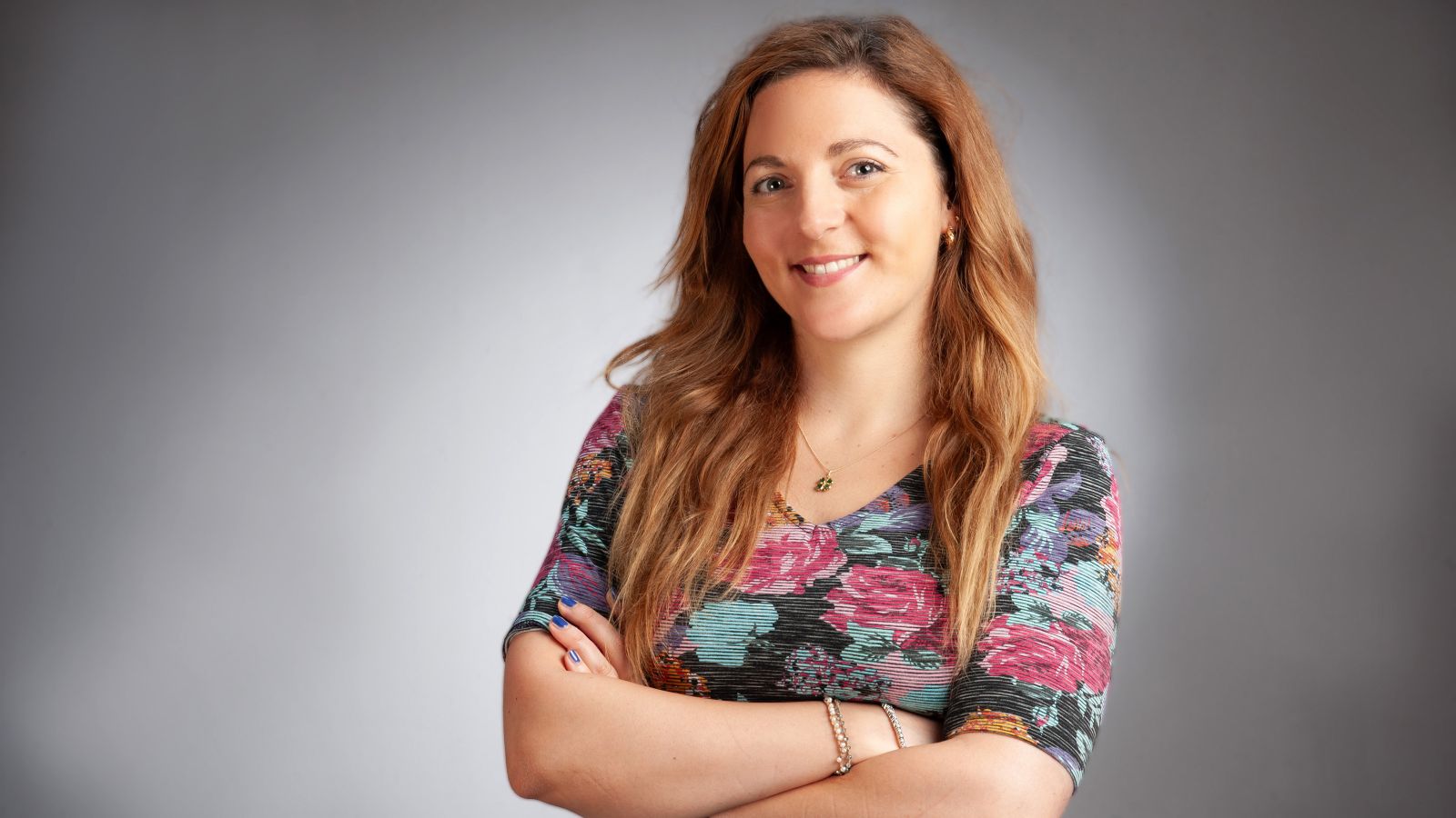 Woman standing with her arms crossed smiling at camera