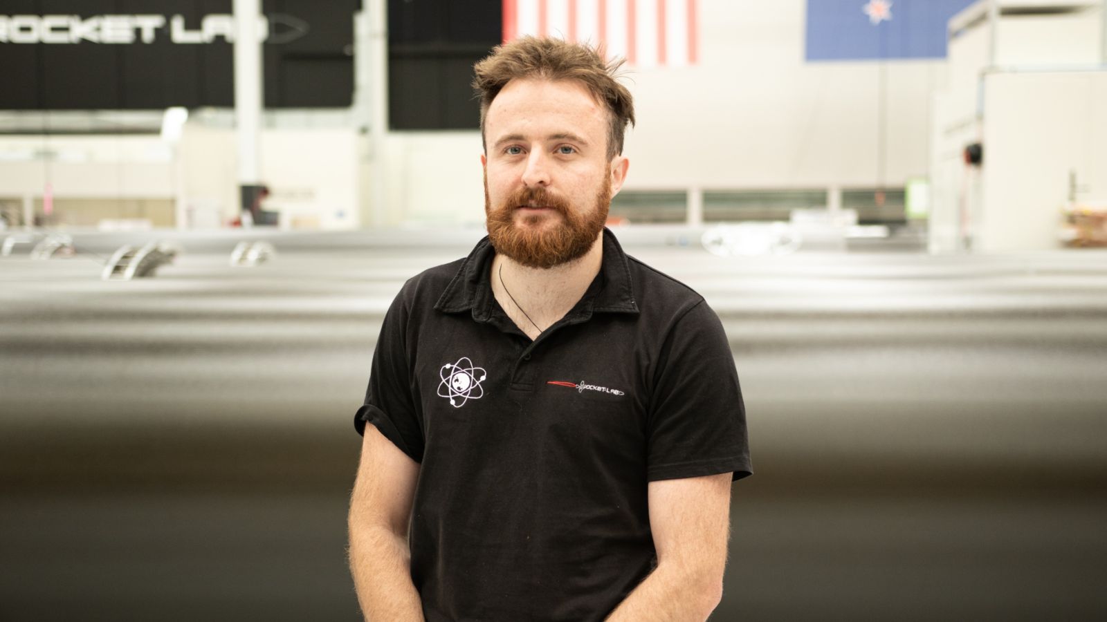 Portrait of Harry Warring standing in front of his workplace, Rocket Lab. Image copyright Rocket Lab, used with permission.