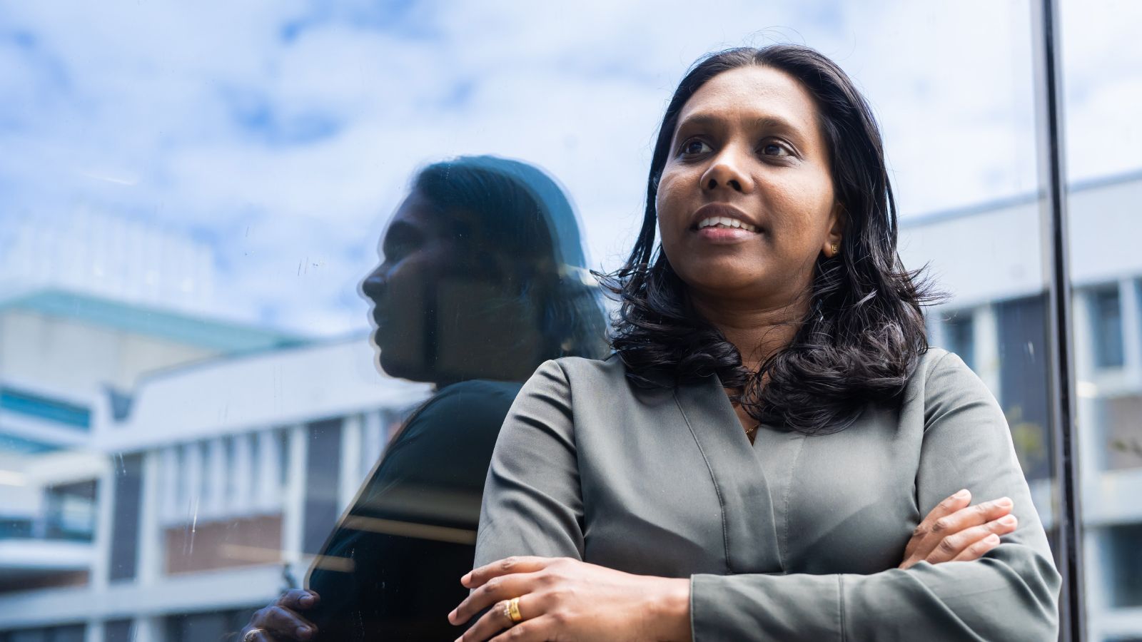 Erandi Nanayakkara Erandi Nanayakkara, with her arms folded, standing in front of her relection in glass.