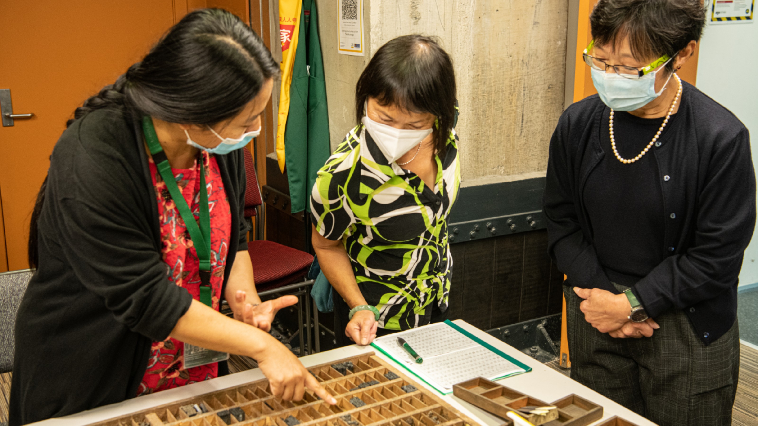three people look at letterpress type in a studio